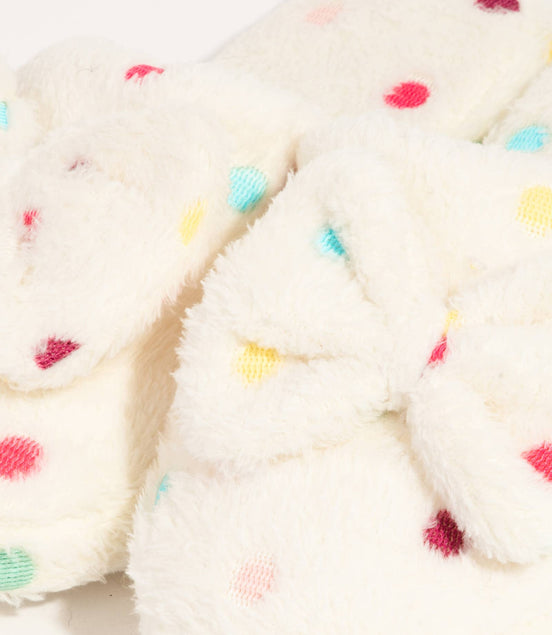 Close-up of a cream-colored fabric with colorful polka dots on a white background