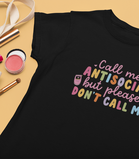 Black t-shirt with colorful text on a beige surface with makeup items.
