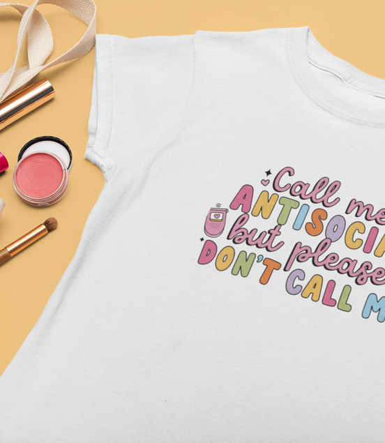 White t-shirt with colorful text design on a yellow background with accessories.