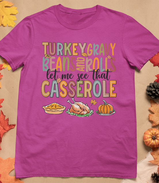 Purple t-shirt with Thanksgiving-themed text and graphics on a fall-themed background
