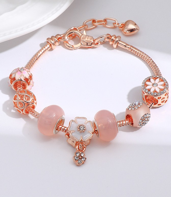 Rose gold bracelet with pink beads on a white background