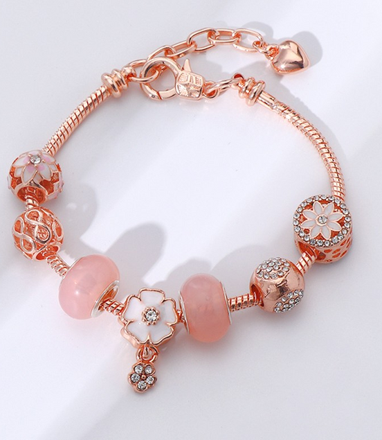 Rose gold bracelet with pink beads on a white background