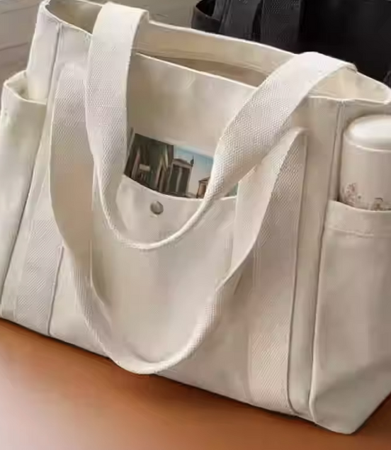 Beige tote bag with multiple pockets on a wooden surface