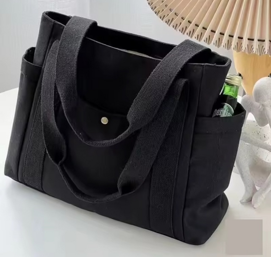 Black tote bag with a pocket on a white surface