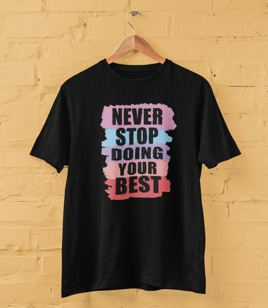 Black t-shirt with motivational quote on a wooden hanger against a yellow brick wall.