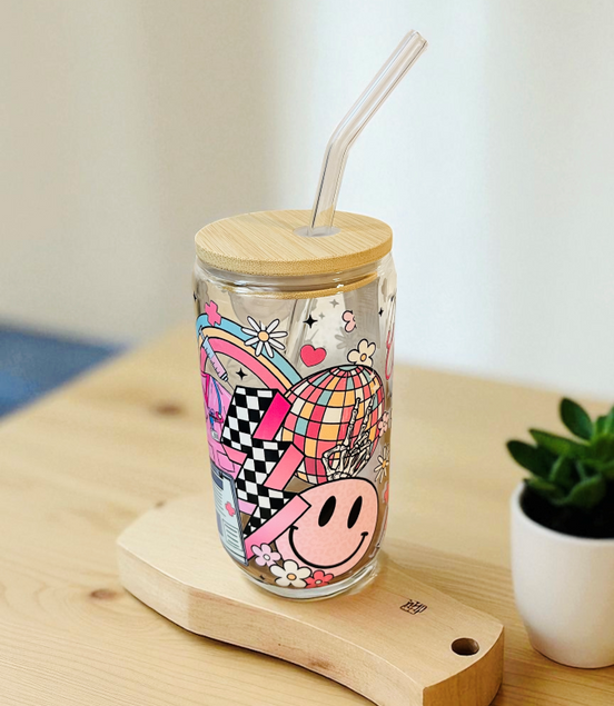Colorful tumbler with a wooden lid and straw on a wooden surface