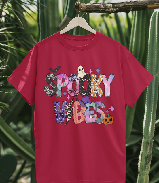 Pink t-shirt with 'Spooky Vibes' text and graphics on a hanger against a cactus background